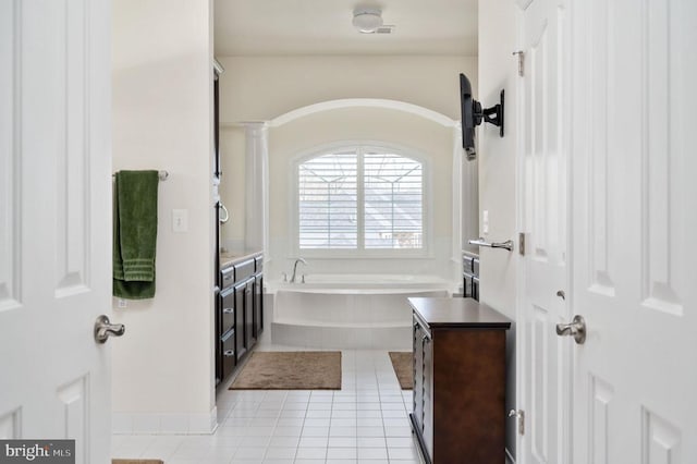 full bath with tile patterned floors, a garden tub, and vanity