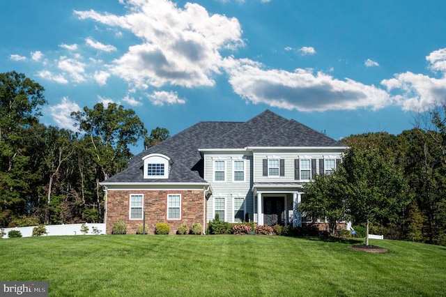 view of front of property featuring stone siding, a front yard, and roof with shingles