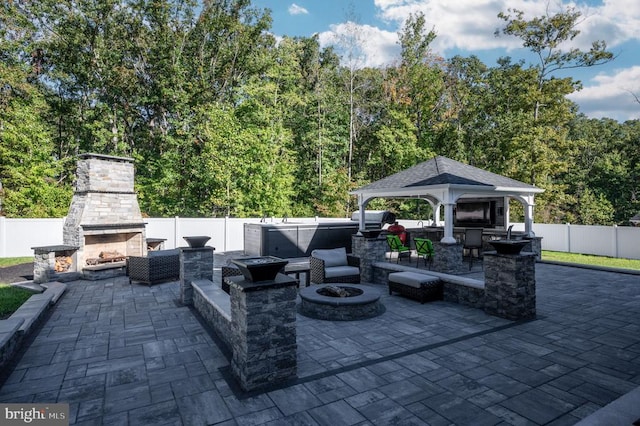 view of patio / terrace featuring a gazebo, an outdoor fire pit, an outdoor stone fireplace, and fence