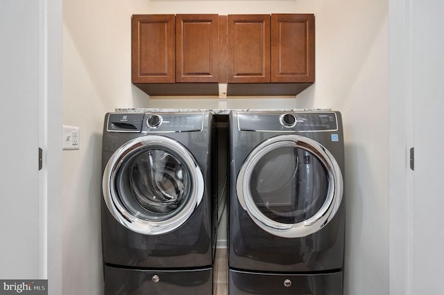 clothes washing area with washing machine and clothes dryer and cabinet space