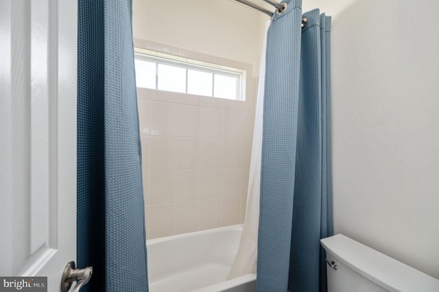 bathroom featuring toilet and shower / tub combo with curtain