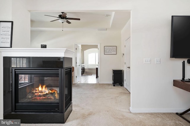 living area featuring visible vents, baseboards, carpet, a multi sided fireplace, and arched walkways