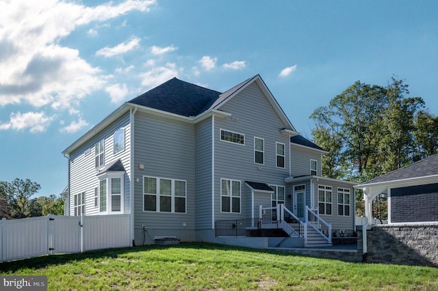 back of house featuring a lawn, fence, a sunroom, and a gate