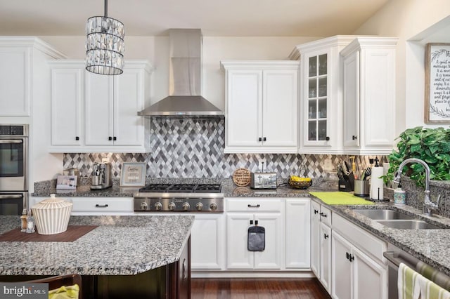 kitchen with tasteful backsplash, appliances with stainless steel finishes, wall chimney range hood, and a sink