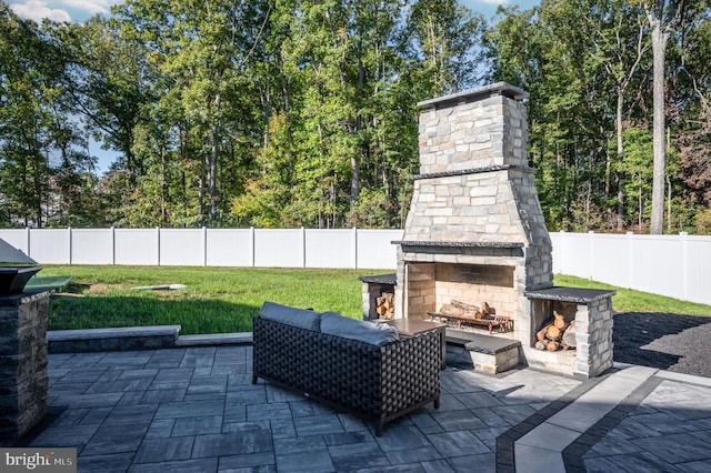 view of patio featuring an outdoor stone fireplace and a fenced backyard