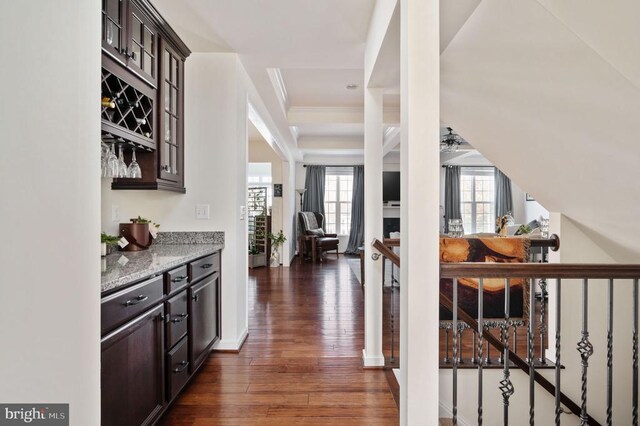 hallway featuring dark wood finished floors, an upstairs landing, baseboards, and ornamental molding