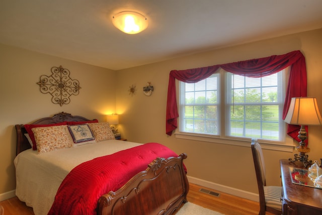 bedroom featuring visible vents, baseboards, and wood finished floors