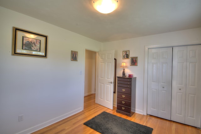 bedroom with light wood-style floors, baseboards, and a closet