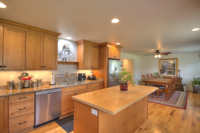 kitchen featuring a sink, butcher block countertops, stainless steel appliances, a ceiling fan, and a kitchen island