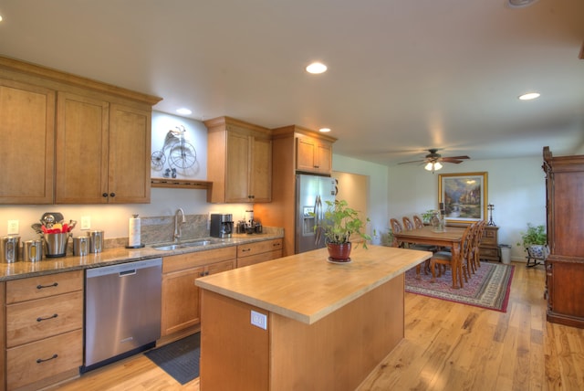 kitchen with butcher block countertops, ceiling fan, a center island, a sink, and stainless steel appliances