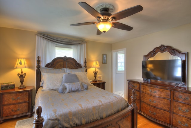 bedroom featuring a ceiling fan, multiple windows, and light wood-style flooring