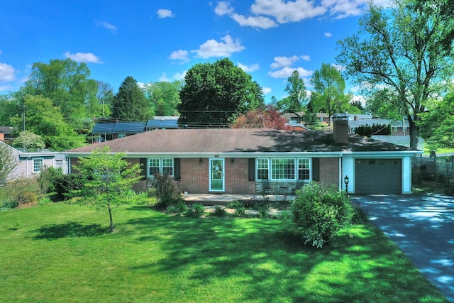 ranch-style home with a garage, a front lawn, aphalt driveway, a chimney, and brick siding