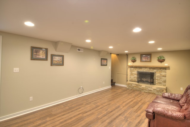 living room featuring recessed lighting, dark wood-style flooring, and a stone fireplace