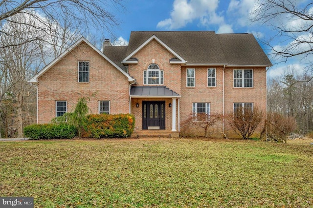 view of front of property featuring brick siding, a yard, and roof with shingles