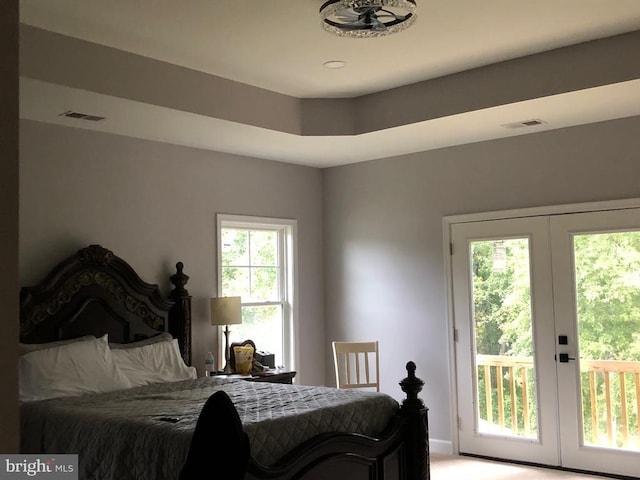 bedroom with french doors, a tray ceiling, and access to outside