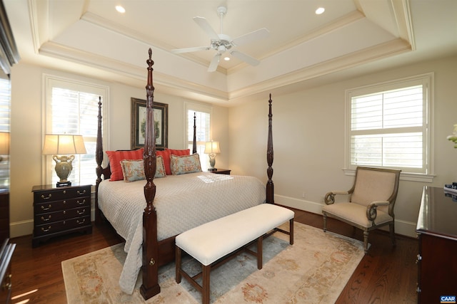 bedroom featuring ornamental molding, dark wood-type flooring, ceiling fan, and a tray ceiling