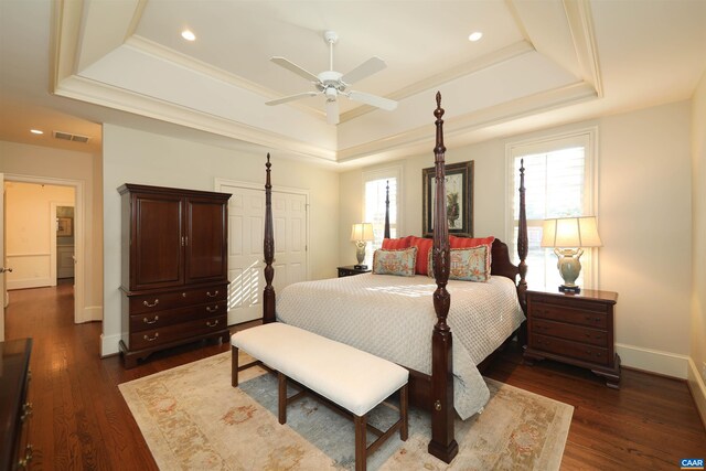 bedroom featuring multiple windows, dark hardwood / wood-style floors, and a tray ceiling