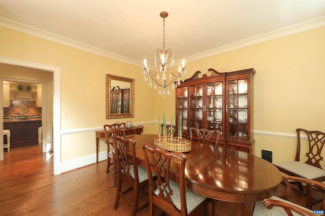 dining area featuring hardwood / wood-style flooring, crown molding, sink, and a chandelier