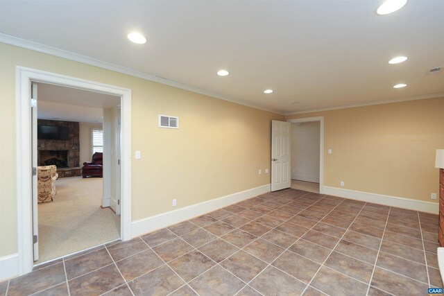 empty room featuring crown molding, a stone fireplace, and tile patterned floors