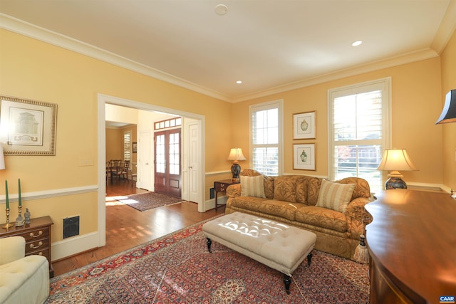 living room featuring ornamental molding, wood-type flooring, and a healthy amount of sunlight