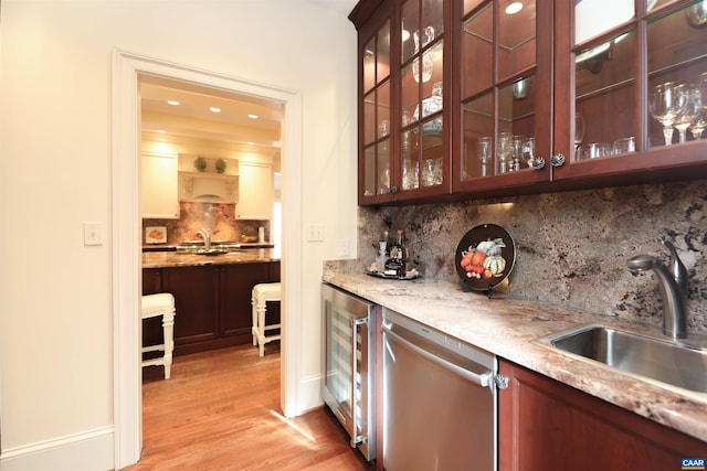 bar featuring wine cooler, sink, stainless steel dishwasher, light stone countertops, and backsplash