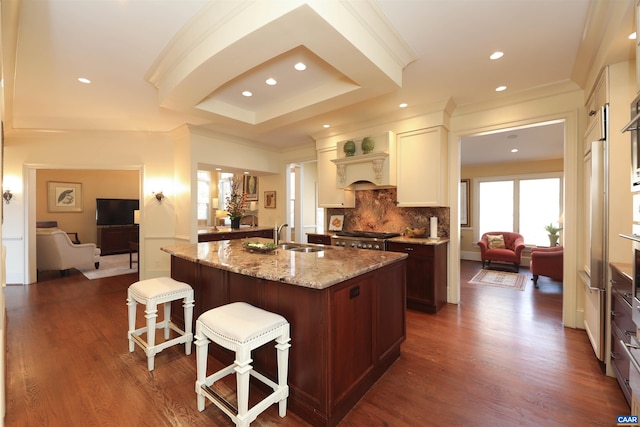 kitchen featuring a kitchen island with sink, light stone countertops, a kitchen breakfast bar, and sink