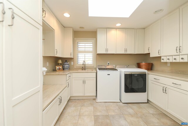 washroom featuring sink, cabinets, a skylight, light tile patterned floors, and washer and clothes dryer