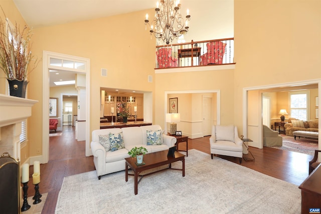 living room featuring an inviting chandelier, wood-type flooring, high vaulted ceiling, and a tile fireplace