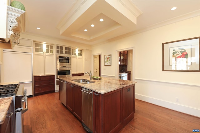 kitchen with light stone counters, ornamental molding, an island with sink, and appliances with stainless steel finishes