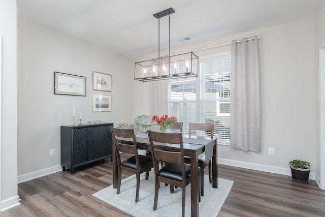 dining room featuring wood finished floors, visible vents, baseboards, and an inviting chandelier