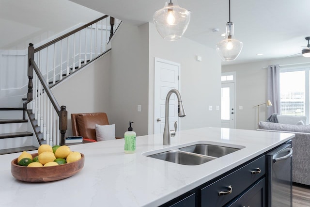 kitchen with a sink, open floor plan, wood finished floors, light stone countertops, and decorative light fixtures