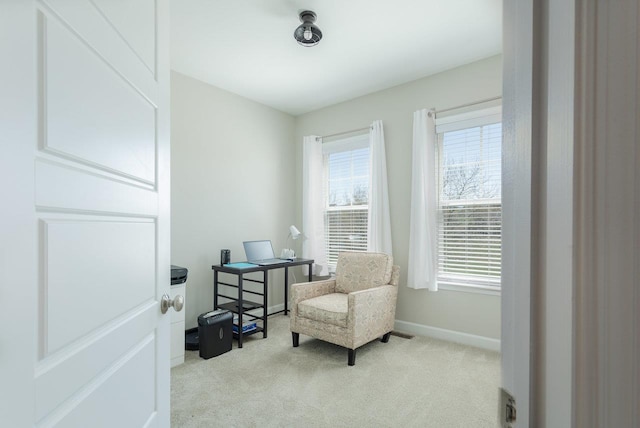 living area featuring baseboards, light colored carpet, and a healthy amount of sunlight