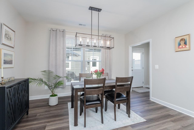 dining space featuring visible vents, baseboards, an inviting chandelier, and dark wood-type flooring