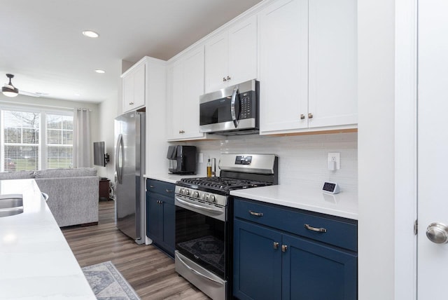 kitchen with light countertops, white cabinetry, blue cabinetry, and appliances with stainless steel finishes