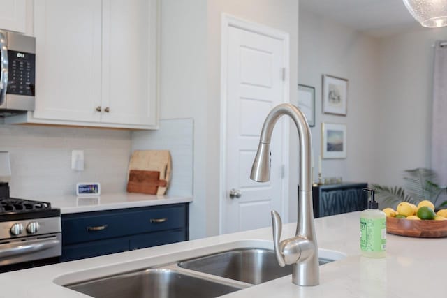 kitchen with backsplash, appliances with stainless steel finishes, white cabinetry, and light countertops