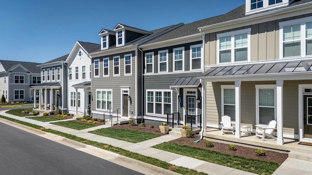 townhome / multi-family property with a standing seam roof, a porch, and board and batten siding