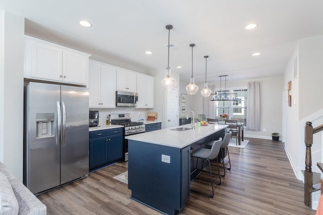 kitchen with white cabinets, recessed lighting, stainless steel appliances, a sink, and blue cabinetry