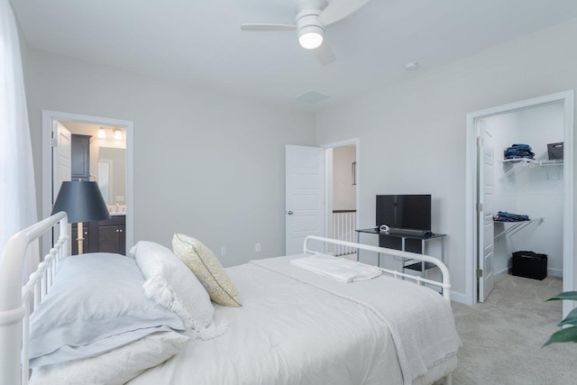 bedroom with a closet, a spacious closet, ceiling fan, light carpet, and ensuite bath
