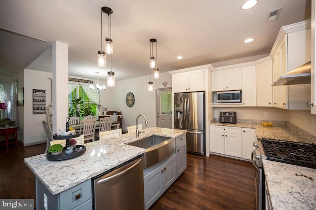 kitchen with appliances with stainless steel finishes, light stone countertops, a sink, white cabinets, and dark wood-type flooring
