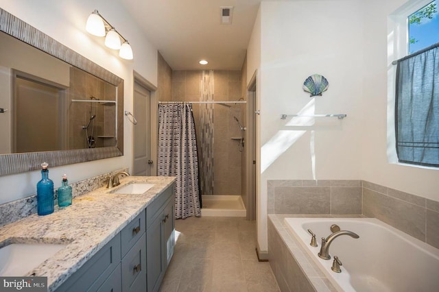 bathroom with double vanity, a garden tub, visible vents, a stall shower, and a sink
