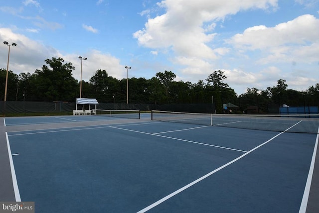 view of tennis court with community basketball court and fence