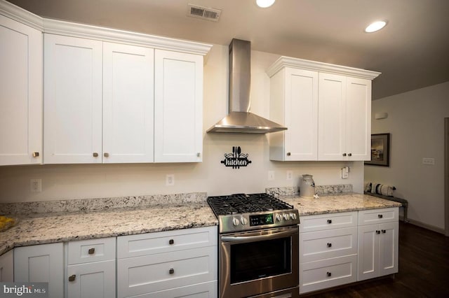 kitchen featuring white cabinetry, stainless steel range with gas cooktop, wall chimney exhaust hood, and visible vents