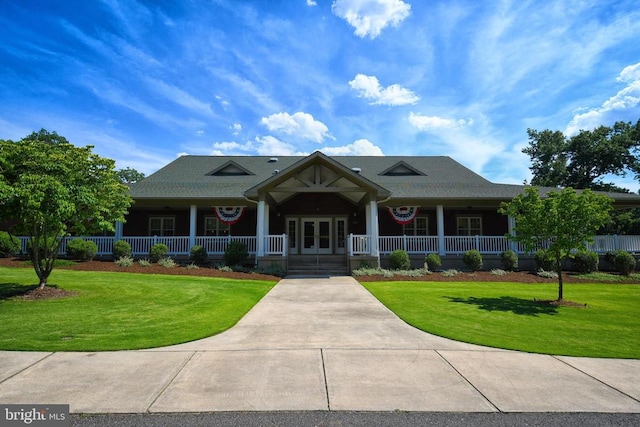 view of front of property featuring french doors, covered porch, and a front yard