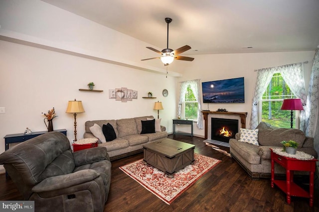 living room featuring dark wood-type flooring, a ceiling fan, a healthy amount of sunlight, and vaulted ceiling