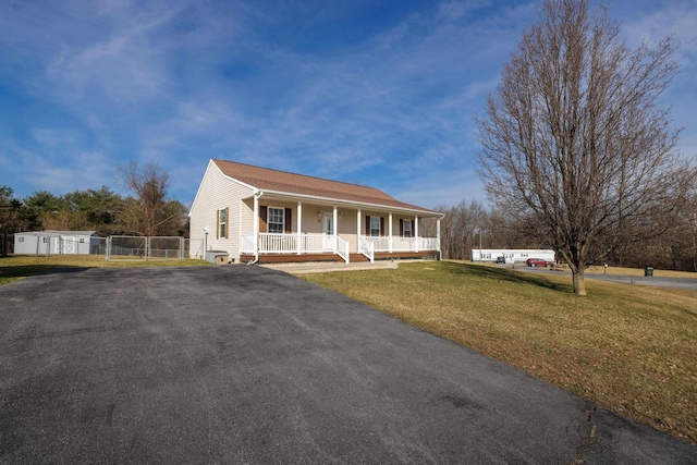 view of front of house with aphalt driveway, covered porch, a front yard, and fence