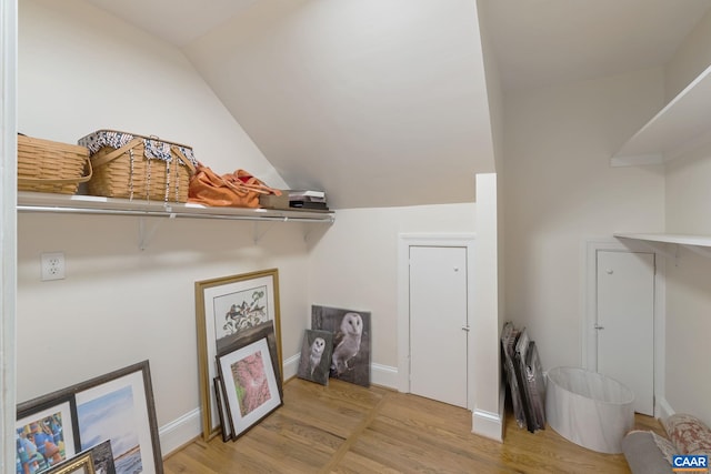 interior space with lofted ceiling, wood finished floors, and baseboards