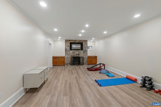 workout area with light wood finished floors, recessed lighting, a fireplace, and crown molding