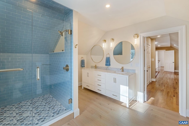 bathroom featuring lofted ceiling, wood finished floors, a stall shower, and a sink