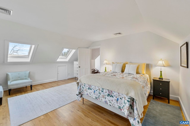 bedroom with visible vents, lofted ceiling with skylight, and wood finished floors