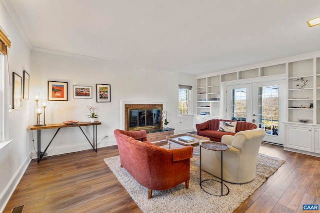 living area featuring a fireplace, built in shelves, french doors, and hardwood / wood-style floors